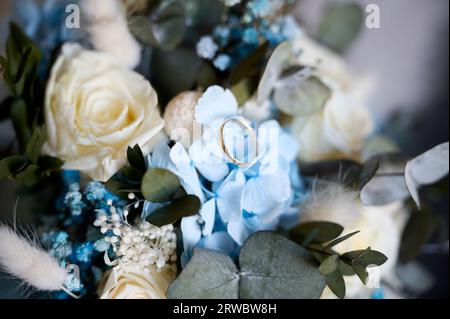 Focused shiny golden wedding ring placed on top of a flower from a bridal bouquet Stock Photo