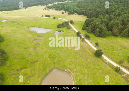 Aerial view of asphalt road going through green and hills covered with grass Stock Photo