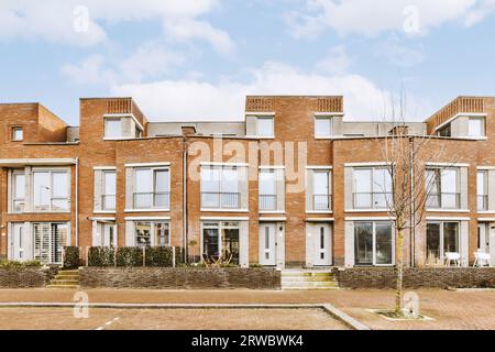 Exterior of apartment building with brick walls and glass windows from an empty sidewalk street on cloudy day Stock Photo