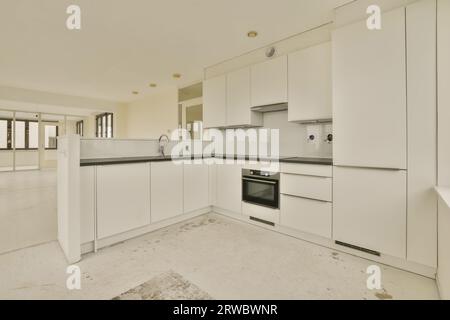 Interior of open plan modern kitchen with white cabinets and black counter in new spacious light apartment Stock Photo