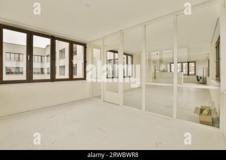 Interior of spacious refurbished apartment with large windows and glass walls between empty rooms with white walls and floor Stock Photo