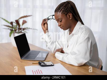Fatigued young african woman working at office Stock Photo