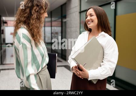 Two Happy Businesswomen Talking And Laughing During Break At Office Stock Photo