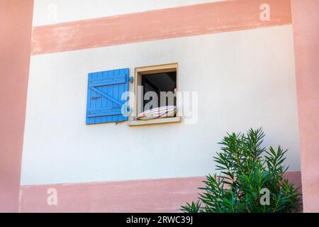 An open glassless window with a blue wooden shutter. Stock Photo