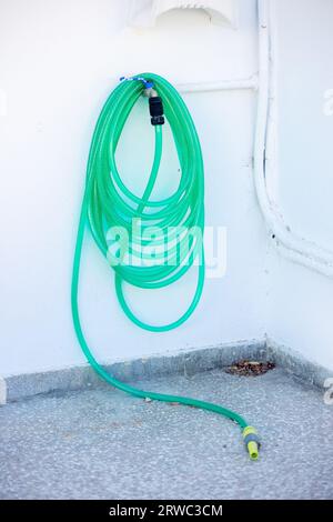 Blue water pipes rolled,blue watering hose rolled on a cement wall. Stock Photo