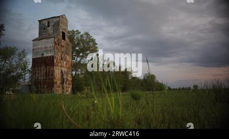 Old grain mill in a meadow of  prairie wildflowers with springtime developing storms. Stock Photo