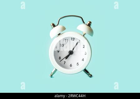 Vintage white alarm clock isolated on blue background. Stock Photo