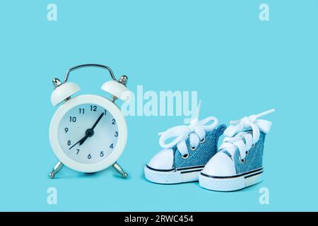 Alarm clock and sneakers on a blue background. The concept of sport and healthy lifestyle. Stock Photo
