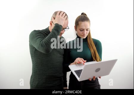 error in work man adult in horror clutching his head young girl calmly holding laptop looking solving problem office workers boss subordinate. institute professor student explain errors Stock Photo