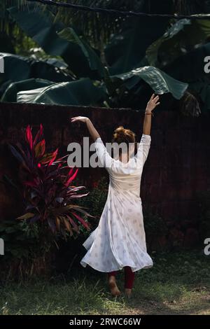 Red haired Caucasian girl is dancing in an Indian white dress. The woman is spinning in dance. Traveling in India. Stock Photo