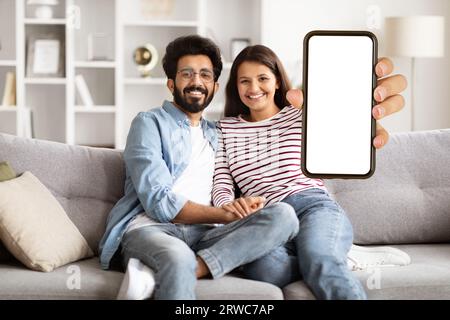 Cute loving indian couple showing smartphone with blank screen Stock Photo