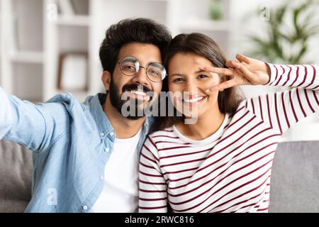 Happy millennial indian couple taking selfie at home Stock Photo
