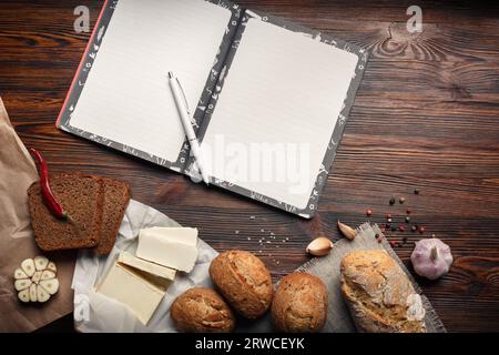 A set of oil, bread, pepper, garlic and notepad on a brown wooden board Stock Photo