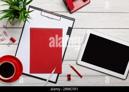 white desktop red cup black coffee clock plug-in tablet phone paperclips pencils puncher clock flower stapler phone headphones workflow start of the w Stock Photo