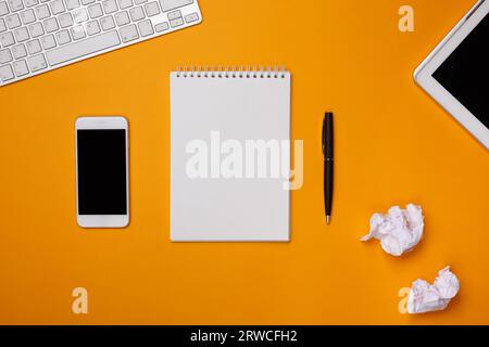 on a yellow background note pad notes desktop keyboard phone pile crumpled paper Stock Photo