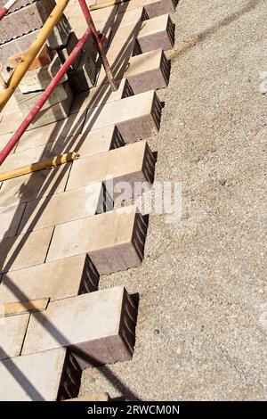 Half-placed cement blocks to create the asphalt of a pedestrian street with fences protecting the work and stacked bricks ready to be placed. Stock Photo