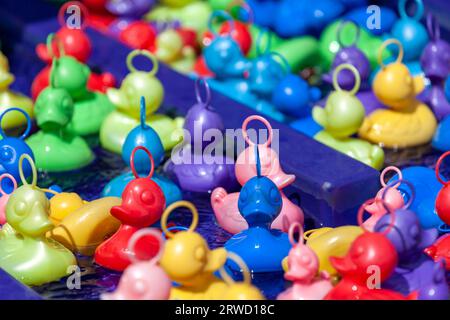 Colorful plastic ducks in the water basin of a traveling carnival stall. Stock Photo
