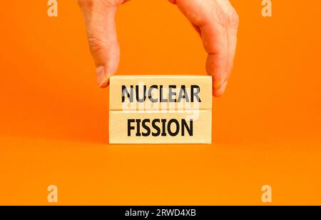 Nuclear fission symbol. Concept words Nuclear fission on beautiful wooden blocks. Beautiful orange table orange background. Businessman hand. Business Stock Photo