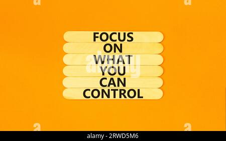 Focus on control symbol. Concept words Focus on what you can control on wooden stick. Beautiful orange table orange background. Business control motiv Stock Photo