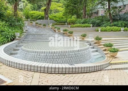 Stone fountain waterfall in Hong Kong Central park on a sunny day in the middle of the city. Hong Kong - 31st August 2023 Stock Photo