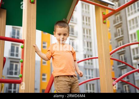 Cute toddler boy two or three years old is playing on the playground in a residential complex. Healthy summer activity for children. Children's games. Stock Photo