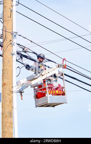 Technician works on new fibre optic cape being installed from the gondola of a bucket truck. Stock Photo