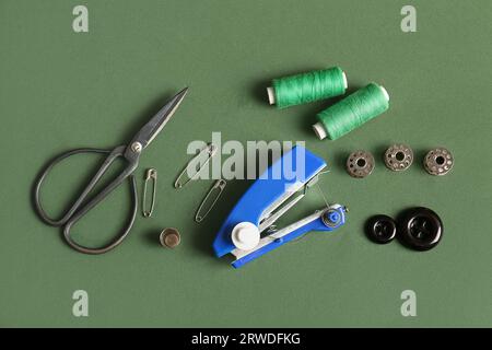 Manual sewing machine with different supplies on green background Stock Photo