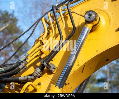Closeup of the hydraulics pipes and fittings and cylinder on a working excavator machine. Stock Photo