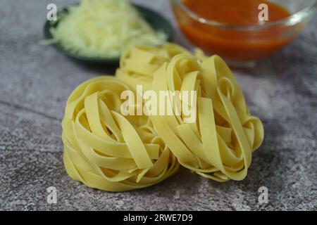 Raw egg tagliatelle pasta with tomato sauce and shredded cheese Stock Photo