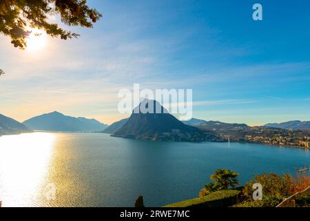 Tree Branch and Lake Lugano and City with Mountain and Blue Sky in Park San Michele in Castagnola in Lugano, Ticino in Switzerland Stock Photo