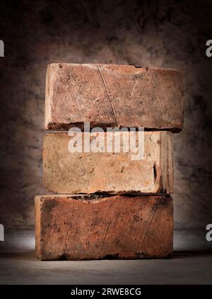 Three old used red clay bricks stacked Stock Photo