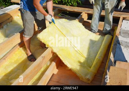 Attic insulation with mineral wool. Roofing contractor measure mineral wool insulation material for cut during attic floor insulation. Stock Photo