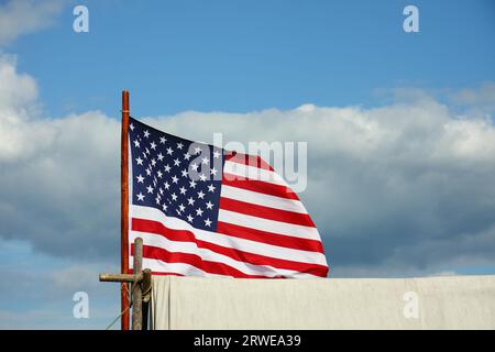 Star-spangled flag on white trapper's tent against blue-white sky, detail Stock Photo