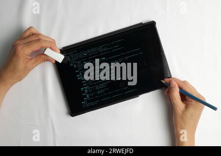 Programming and coding concept. Code generation: listing screen and two hands, one holding a pencil and the other holding an eraser Stock Photo