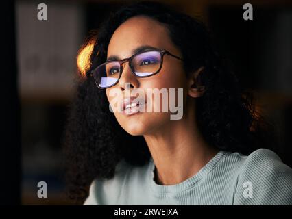 Business woman, glasses and reading on computer for programming, software or information technology solution. Young night programmer in screen Stock Photo