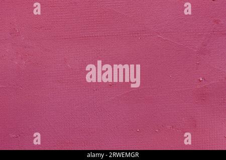Uneven stucco wall painted dark rose pink. Grungy texture wall Stock Photo