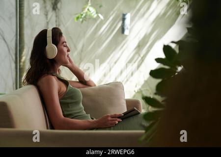 Young woman closing eyes when listening to music in headphones Stock Photo