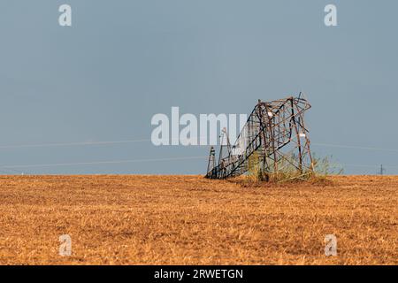 Bent over electricity pylon after strong summer storm, climate change consequences Stock Photo