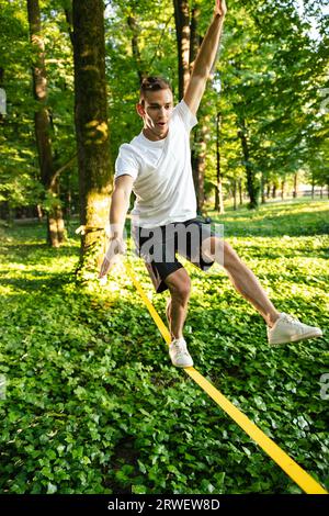 Young man in white tshirt and shorts on the rope keeping balance Stock Photo