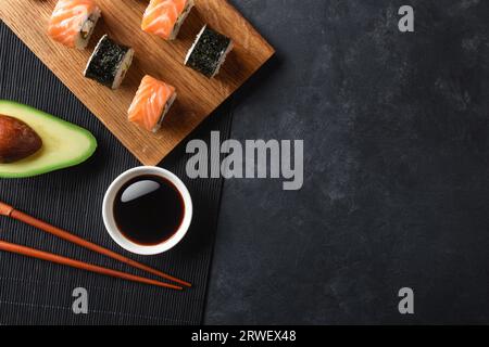 Set of sushi and maki rolls with sliced avocado on stone table. Top view. Stock Photo