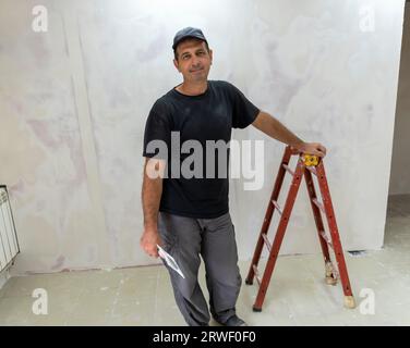 Male builder, master office, plasterer with a tool in working clothes Stock Photo