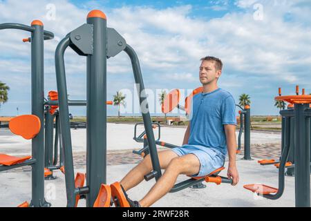 Active man exercising at outdoor gym. Young male doing leg muscle exercises on street playground. Fitness, sport, exercising, training, workout and Stock Photo