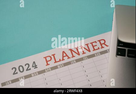 2024 Planner with computer laptop. Top view with copy space. Stock Photo