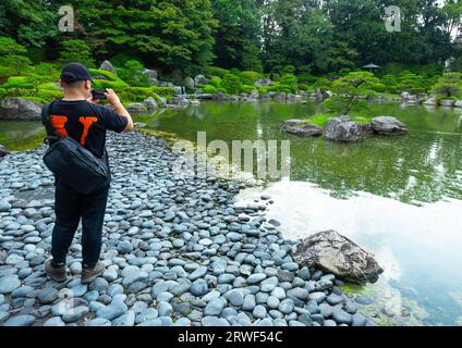 Tourist taking pictures in Ohori Park Japanese Garden, Kyushu region, Fukuoka, Japan Stock Photo