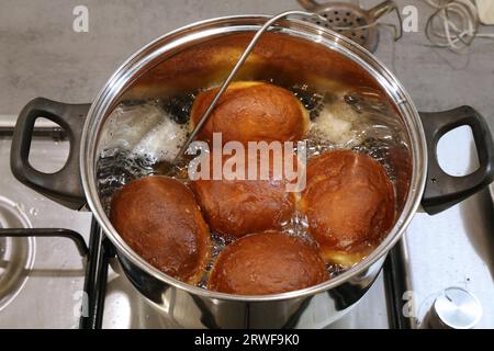 Making homemade yeast raised donuts - deep frying in lard fat with a kitchen thermometer probe. Polish donuts made for Tlusty Czwartek (Fat Thursday) Stock Photo