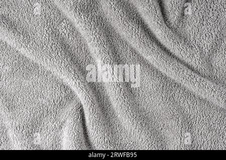 Terry cloth, gray towel texture background. Wrinkled and crumped soft fluffy textile bath or beach towel material. Top view, close up. Stock Photo