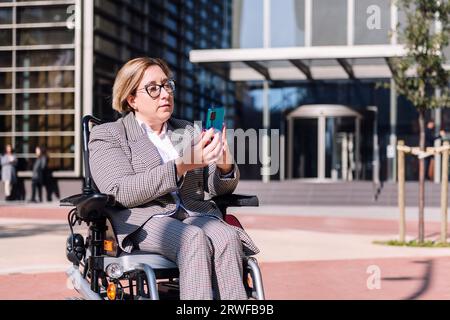 businesswoman using wheelchair using mobile phone Stock Photo