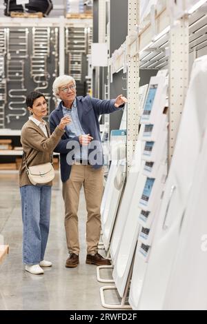 Vertical full length portrait of senior couple choosing tub and bathroom fittings in home improvement store Stock Photo