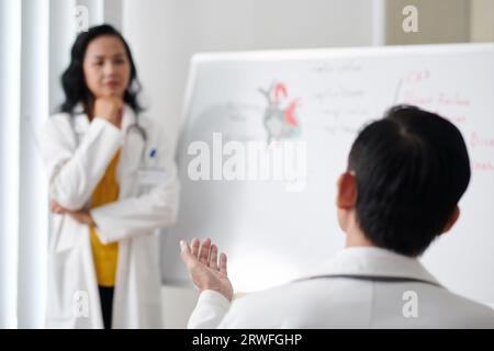 Doctor asking question in seminar with prominent cardiologist Stock Photo