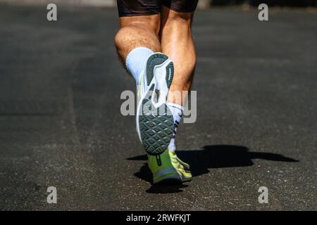close-up sole running shoe and legs male runner, background dark road, marathon race Stock Photo